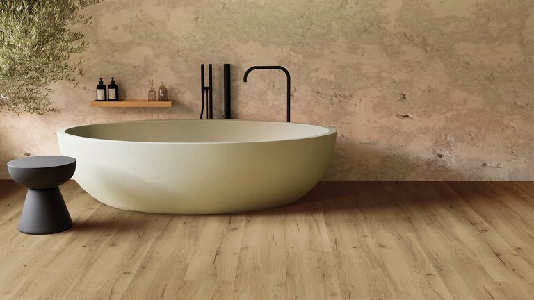 Badezimmer mit freistehender Badewanne und verlegtem hellem Holzboden in natürlicher Holzoptik